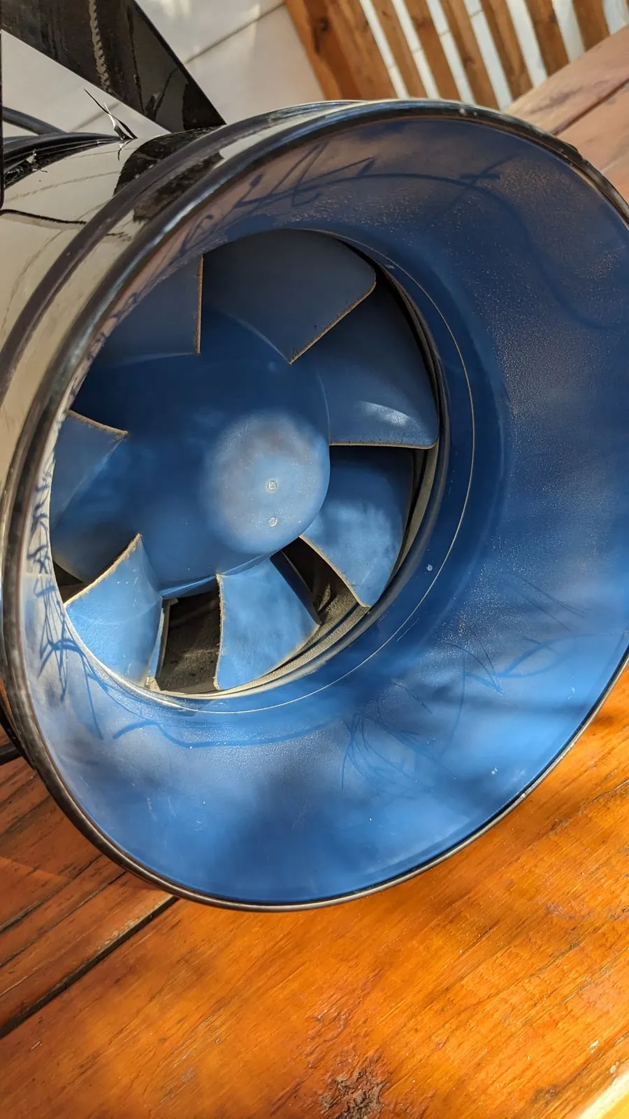 Blue blades of an 8-inch inline duct fan with a film of dust after a year of operation
